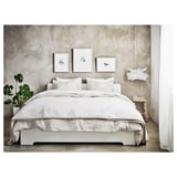 Modern minimalist bed with white linen, plant, and wall art. Low profile, perfect under windows.