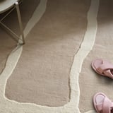 Beige-ivory patterned rug with high-low piles, chair, pink slides.