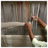 Person weaving on a loom, focusing on intricate pattern creation with threads.