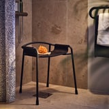Black shower stool with armrests, non-slip feet, and hole-drained seat; ideal for bathroom use.