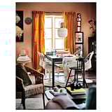 Cozy dining room with orange curtains, white swivel chairs, wooden table, and floral decor.
