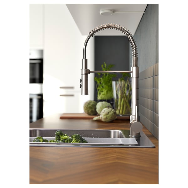 Modern kitchen with stainless steel faucet, broccoli in sink, wooden countertop.