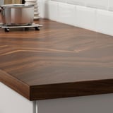 Dark brown wooden countertop with visible grain patterns, suggesting natural durability and aesthetic appeal, supported by metal brackets.