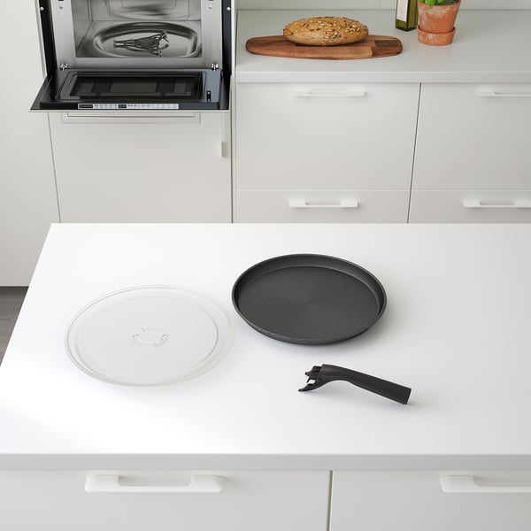 Modern kitchen setup with built-in microwave, featuring crisp plate and handle on counter, near a loaf of bread.