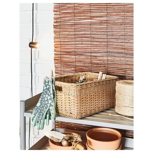 Handwoven BEKNA basket on metal shelf, next to hanging gloves and pots.