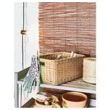 Handwoven BEKNA basket on metal shelf, next to hanging gloves and pots.