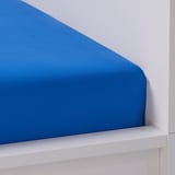 Bright blue bed sheet on white shelf; smooth texture visible.