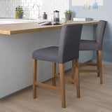 Two BERGMUND bar stools by kitchen island with coffee maker. Sleek, cushioned, removable covers.
