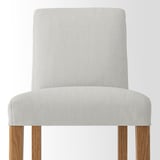 A modern grey upholstered bar stool with comfortable cushions and sturdy wooden legs.