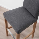 A grey upholstered bar stool with a wooden base and metal footrest for comfort and support.