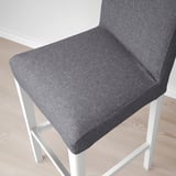 Close-up of a modern, cushioned grey stool with white metal legs. Soft, inviting upholstery.