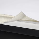 Folded white washable chair cover placed on black surface.