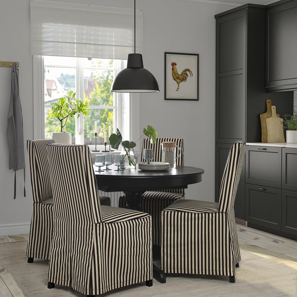 Chic dining scene with round table, striped chairs, black pendant lamp, and grey walls. A framed rooster art adorns the wall above the table.