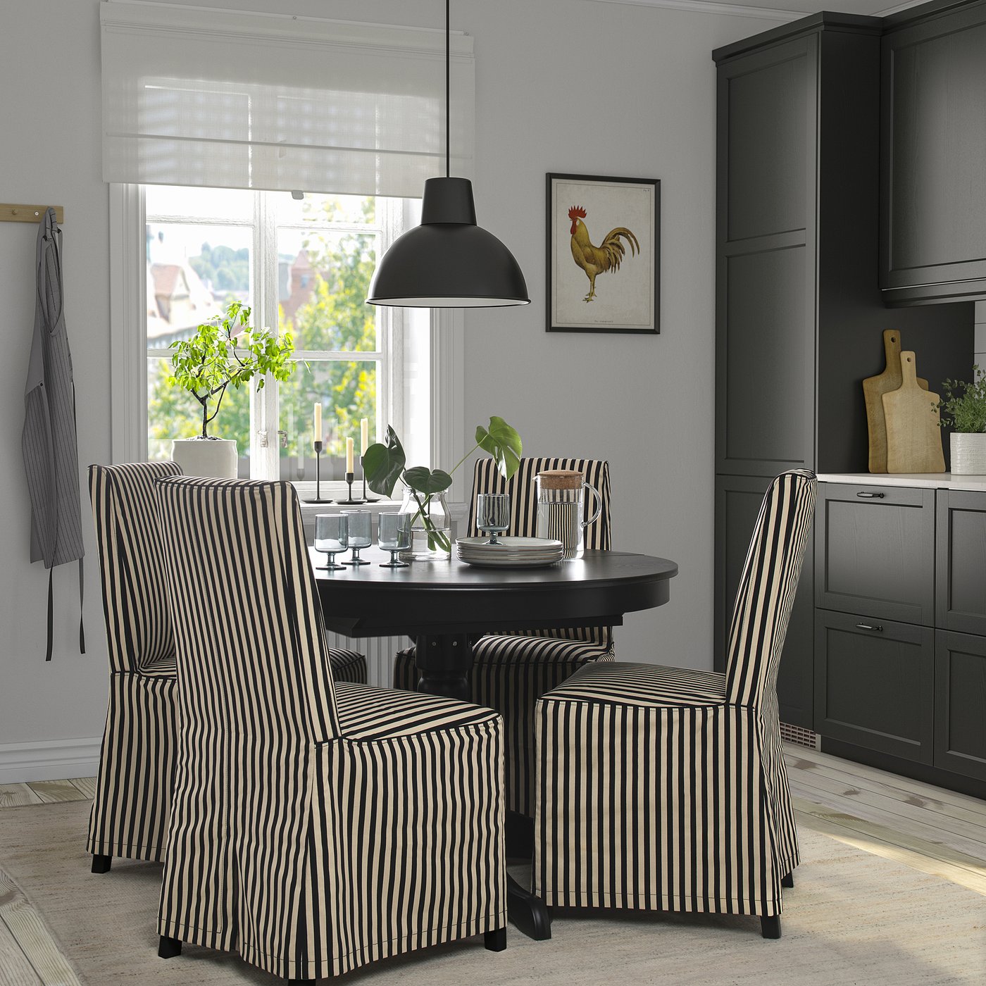 Chic dining scene with round table, striped chairs, black pendant lamp, and grey walls. A framed rooster art adorns the wall above the table.
