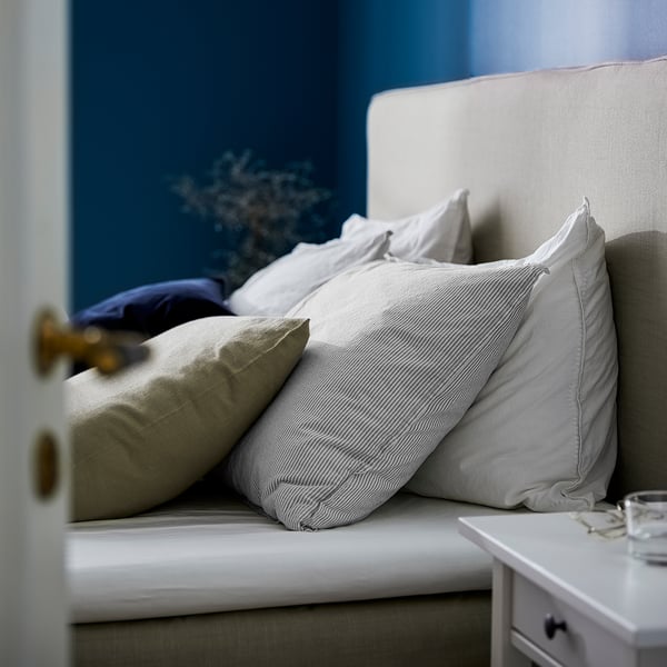 Pillows stacked on bed, featuring white & striped gray BERGPALM cases, soft cotton, classic striped design.