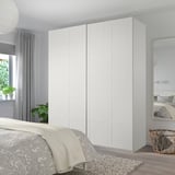 A white BERGSBO sliding closet door in a bedroom with a mirror. The door is modern, large, and sleek, blending seamlessly with its surroundings.