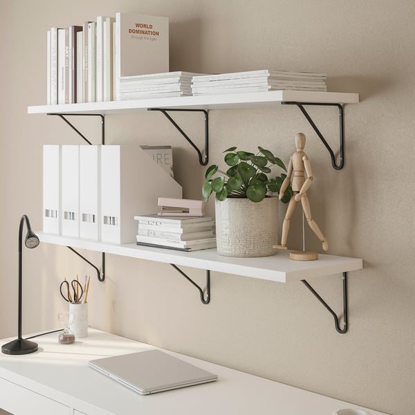 Wall-mounted shelves display books, binders, and decorative items for workspace storage and organization.