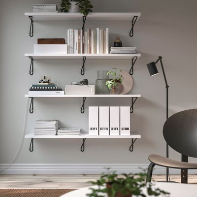 White wall shelf with black brackets holds books & decor, sleek & modern.