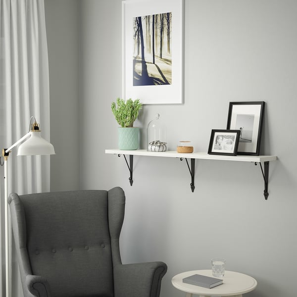 Cozy corner with gray wingback chair under white shelf with mint planter and decor.