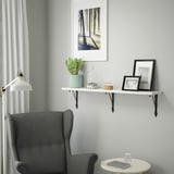 Cozy corner with gray wingback chair under white shelf with mint planter and decor.