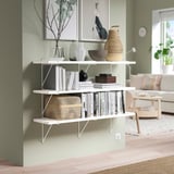 Modern living room with BERGSHULT wall shelf holding decorative items, green wall, and wooden floor.