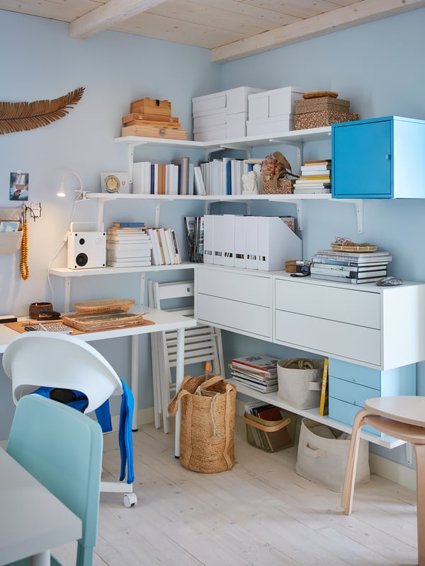 Home office with BERGSHULT shelves, books, light blue furniture, and wood floors.