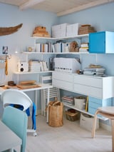 Home office with BERGSHULT shelves, books, light blue furniture, and wood floors.