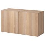 An ikea BESTÅ storage unit in light wood color, featuring two closed cabinet doors.