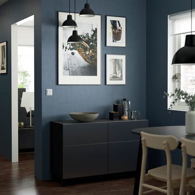 Grey BESTÅ sideboard with lights, decor, & storage. White chairs, art, blue wall.