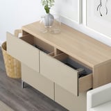 Modern wooden sideboard with open drawer showing remote, featuring sleek design, storage space, and integrated soft-close mechanism.