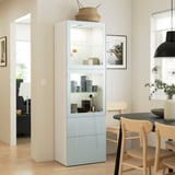 Modern living room with blue BESTÅ cabinet and dishes, between dining table and chair, under black pendant lamp.