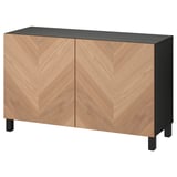 An ikea BESTÅ sideboard in light wood with a black top and legs. It has two doors featuring a chevron wood pattern with soft-closing hinges.