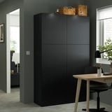 This image shows a tall, black BESTÅ storage unit, larger than a nearby desk, with woven baskets on top.