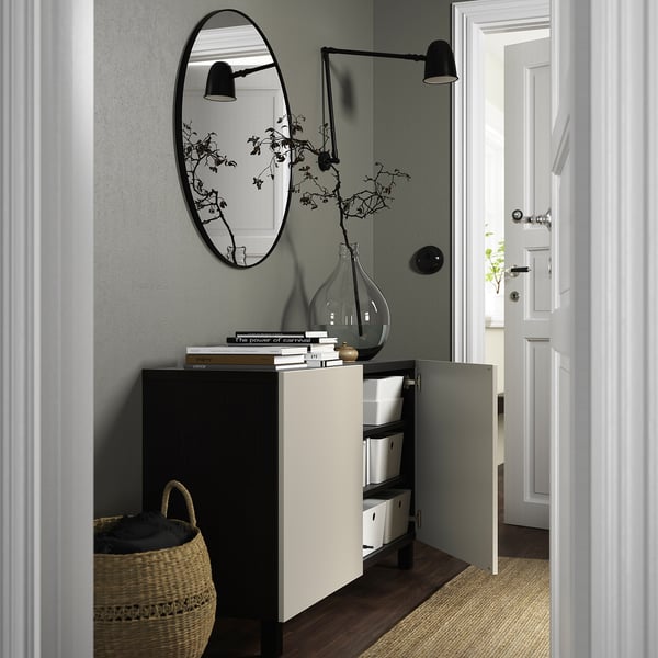 A modern entryway cabinet with adjustable shelves and soft-closing doors, topped with books and a vase.