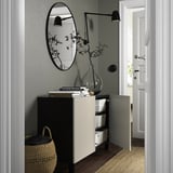 A modern entryway cabinet with adjustable shelves and soft-closing doors, topped with books and a vase.