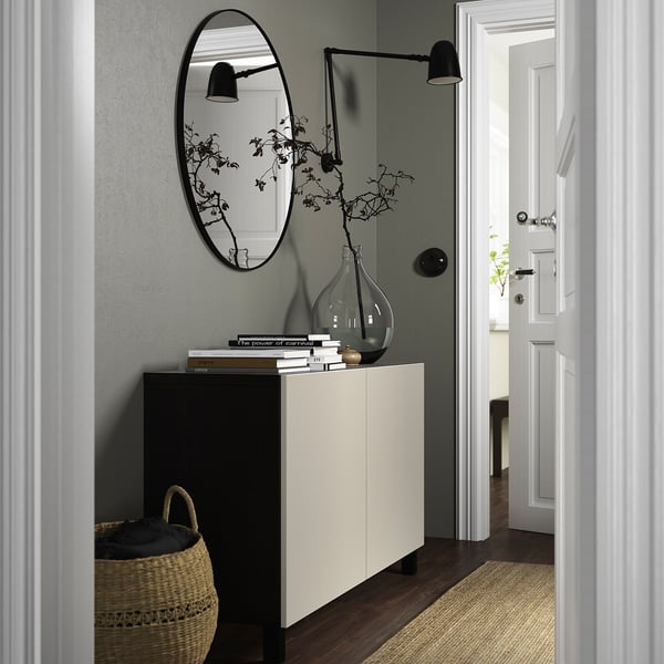 A BESTÅ white sideboard in hallway, mirror above with books, vase, basket.
