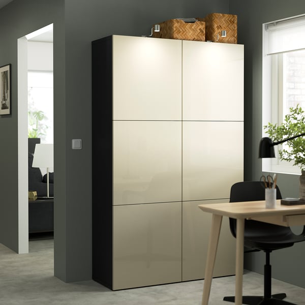 Modern tall white BESTÅ cabinet with beads on top, near a wooden table and chair, in a minimalist room.