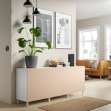 BESTÅ sideboard with veneer door in room. Multiple compartments, topped with decor, against wall with artwork and lamps.