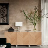 Wooden sideboard, minimalist design, beige finish. White lamp, glass vase with plants, and black framed picture.