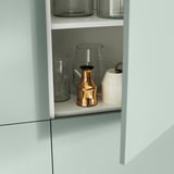 A light blue BESTÅ shelf with glassware and a bronze vase.