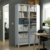 BESTÅ storage unit with shelves holding books, decor, and boxes. Mixed open/closed storage near desk and chair.