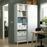 BESTÅ storage unit with books, boxes, and decor in room.