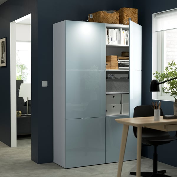 Modern storage unit with glass doors showcasing organized items. Includes shelves for books and boxes. The unit is integrated with office furniture.