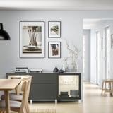 Minimalist living room with BESTÅ sideboard, framed photos, and vase.