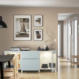 Modern dining room with BESTÅ sideboard featuring adjustable shelves and drawers, displaying dishes and vases, with framed photos on wall.
