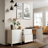 Modern living room with white sideboard. It has open drawers showing storage, a vase with flowers, and framed photos on the wall above.