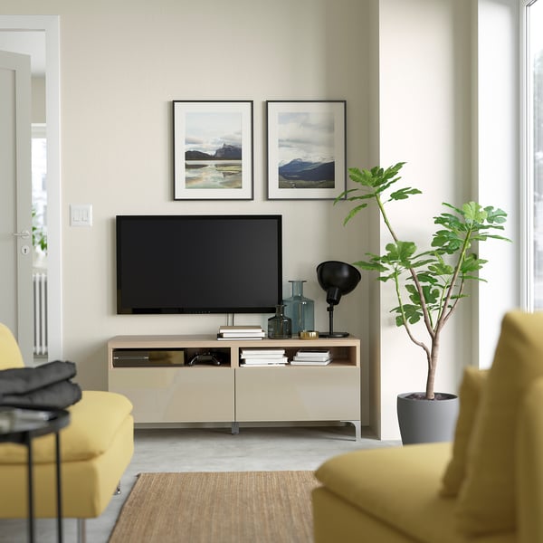 Modern living room with BESTÅ tv bench, flat-screen tv, yellow couch, photos, and plant.