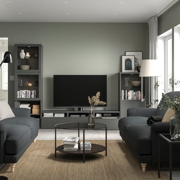 Modern living room with BESTÅ tv bench, flat-screen tv, gray sofas, and glass coffee table.