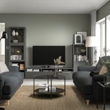 Modern living room with BESTÅ tv bench, flat-screen tv, gray sofas, and glass coffee table.