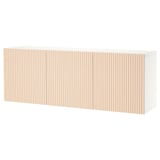 A white BESTÅ storage unit with wooden slatted doors. It stands against a wall, providing a clean and modern look.